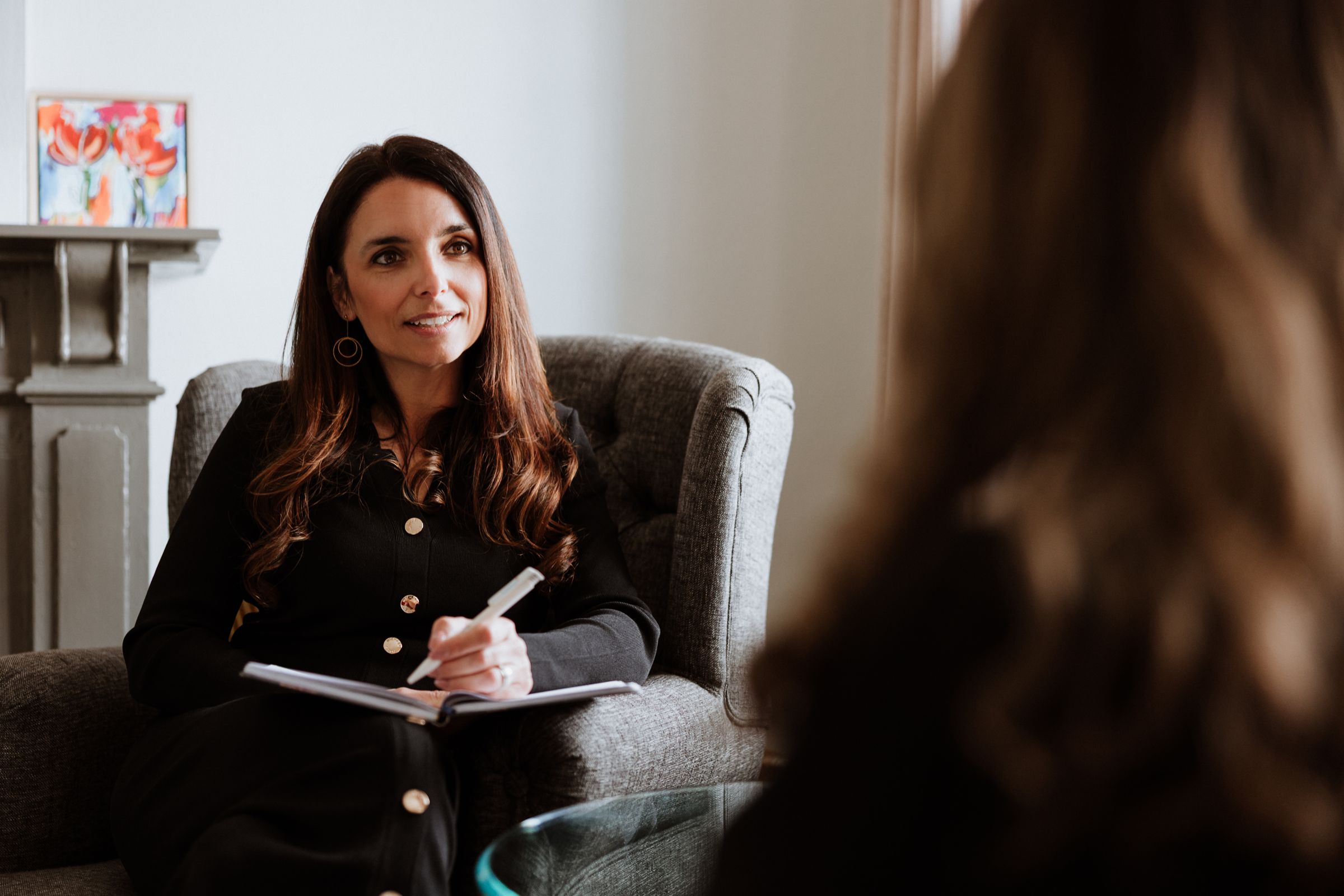 Joyce Schiffers in gesprek tijdens een coachsessie, in een fauteuil met een notitieboek